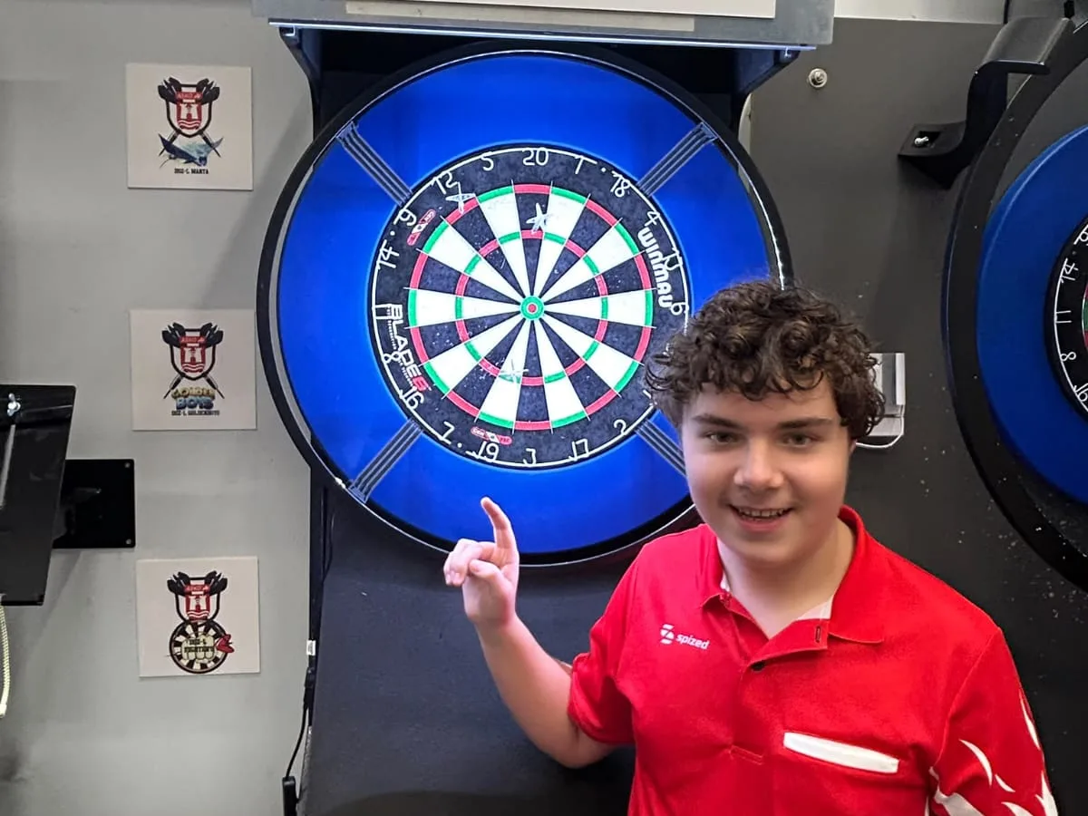 Oliver Szabados zeigt auf die Dartscheibe mit seinen drei Checkdarts